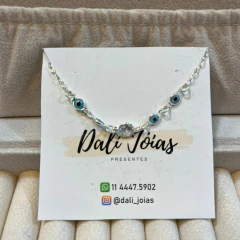 Pulseira em prata 925 com detalhes de olho grego e zircônias, apresentada sobre uma embalagem da Dali Joias.