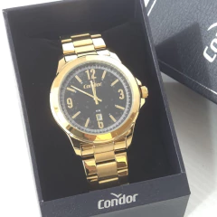 Relógio masculino Condor com pulseira e caixa dourada, mostrador preto com números e detalhes dourados, dentro de caixa preta da marca Condor
