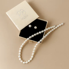 Conjunto de joias com colar de pérolas e brincos de pérola em caixa creme com interior preto