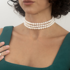 Choker Pérola do Tempo, um colar elegante com várias fileiras de pérolas, usado por uma mulher com vestido verde.