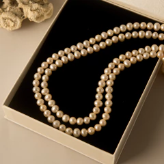 Colar orla dourada com pérolas naturais exibido em caixa de presente preta com borda bege