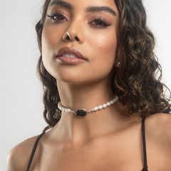 Colar Raiz com pérolas e detalhe em pedra negra, exibido em uma modelo.