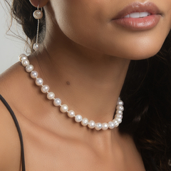 Colar de pérolas brancas usado por uma mulher, destacando a elegância e o estilo do acessório.