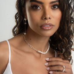 Modelo usando colar de pérolas com detalhes em metal e brincos combinando, destacando a elegância do acessório.