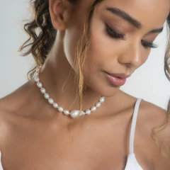 Modelo usando um colar barroco de pérolas brancas, com um olhar suave e elegante.