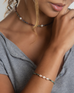 Pulseira Esmeralda com pérolas, usada no braço de uma modelo, destacando seu design elegante.