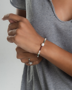 Pulseira Riviera com pérolas e pedras coloridas, adornando o pulso de uma modelo.