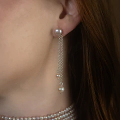 Brinco Brisa G com pérolas e correntes prateadas penduradas em orelha feminina, estilo delicado e elegante