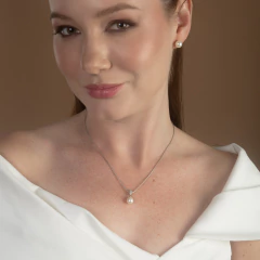 Colar delicado com pingente de pérola branca em corrente prateada usado no pescoço de mulher