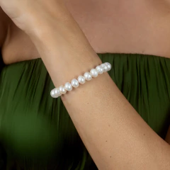 Pulseira Unique de pérolas brancas usada no pulso de mulher com vestido verde