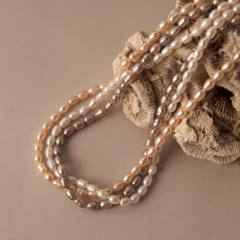 Mulher usando colar Duna triplo com pérolas em tons branco, dourado e rosé