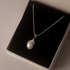 Mulher usando colar com pingente de pérola e brincos combinando