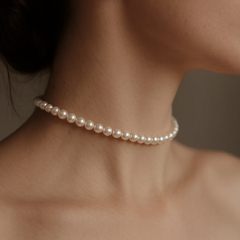 Gargantilha de pérolas clássica adornando o pescoço de uma mulher.