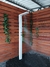 Ducha de piso em aço inox com jatos brancos em um espaço externo, cercada por paredes de madeira e plantas.