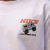 Camisa branca com estampas coloridas da Nike, incluindo um veículo 4x4 e a frase "FORWARD MOTION".
