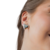 Aretes en forma de corazón, color plateado, usados por una mujer.
