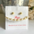 Set de aretes y pulsera en tonos dorados y perlas, presentado en una tarjeta blanca con detalles rojos.