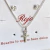 Conjunto de joyería que incluye un collar con cruz plateada y aretes con piedras brillantes.
