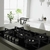 Anafe a gas Whirlpool de vidrio templado de 73 cm, con cinco hornallas y diseño moderno, en una cocina minimalista con ventana y plantas.