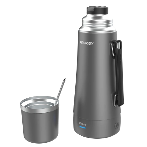 Termo eléctrico Peabody E-Termo de 1 litro en color gris oscuro, acompañado de una taza de acero inoxidable y una cuchara.
