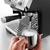 Una persona usando la cafetera express DeLonghi Specialista Arte EC9155 para espumar leche en un recipiente de acero inoxidable.