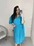 Modelo usando um vestido azul claro Mirella Plus Size, com detalhes em bolinhas e cintura marcada, posando em frente ao espelho.