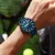 Relógio Curren masculino com design moderno e pulseira azul, usado no pulso de um homem em ambiente externo