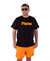 Modelo usando a camiseta Pleno Laranja Cenoura®️, com fundo branco e shorts laranja.