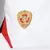 Detalhe do escudo da Camisa São Paulo I 25/26 da New Balance, destacando o símbolo em dourado e vermelho.