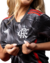 Camisa de futebol do Flamengo, modelo third da Adidas, sendo segurada por uma mulher, destacando o logo do time em um fundo preto geométrico.