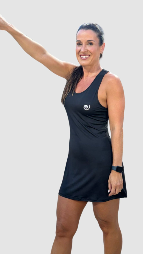 Modelo usando um vestido preto Nadine, com um design elegante e confortável, posando com um braço levantado.