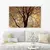 Quadro decorativo com galhos secos sobre fundo laranja, emoldurado, decorando uma sala de estar.