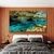 Quadro decorativo da Pratinha, uma caverna com água cristalina em tons de azul e verde, embelezando uma parede de madeira ao lado de uma cama.