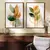 Dois quadros decorativos com ilustrações de flores em tons de verde e laranja, emoldurados em madeira, decorando uma parede.