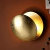 Arandela de parede modelo Eclipse com acabamento dourado, montada em uma parede laranja.