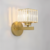 Luminária de parede luxuosa com acabamento em cristal e base dourada.