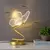 Luminária de mesa em formato de borboleta, com base dourada e luz LED, ideal para quartos.