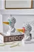 Escultura Grega Nórdica Sherbet com detalhes de sorvete colorido, decorando uma mesa com livros e pérolas.