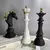 Escultura decorativa de xadrez com rei, rainha e cavalo, em cores preto e branco, com detalhes em dourado.