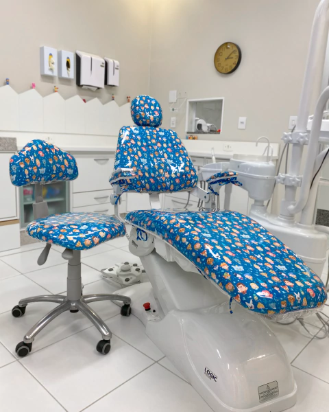 Kit Completo Instalado	Kit Classic instalado em cadeira odontológica: capa de tecido oxford colorido por baixo da capa plástica transparente 0.20mm. Dupla proteção.
Detalhe da Dupla Camada	Close-up da sobreposição da capa de tecido e do plástico incolor, 