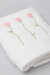 Toalla de visita blanca de 100% algodón con bordado de flores en tonos rosa y verde.