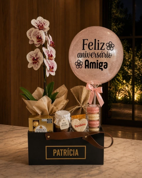 Box Cartonada Premium com orquídea, caixa de Ferrero Rocher, geleia artesanal, biscoito em formato de coração com a palavra "Parabéns", macarons empilhados e balão rosa com a frase "Feliz aniversário Amiga".