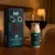 Gel Beijável Vibration Vinho Tinto destacado em um quarto aconchegante com duas taças de vinho em Pega Fogo | Sex Shop Online.
