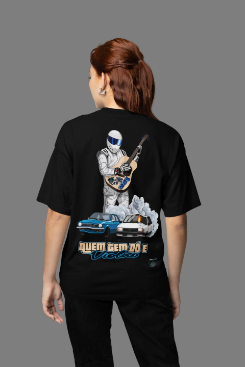 Camiseta oversized preta com estampa de um personagem segurando um violão e dois carros clássicos, um Chevette e outro modelo, com a frase "Quem tem dó e violão".