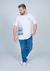 Camiseta branca plus size com estampa de praia e frase motivacional, modelo masculino, usando jeans e tênis brancos.