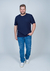 Camiseta plus size azul marinho em malha relevo, modelo masculino, com jeans e tênis, em fundo neutro.