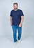Camiseta plus size azul marinho com gola careca, modelo estampado, usado por um homem em pé, com jeans e tênis brancos.