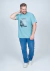 Camiseta plus size azul claro com estampa frontal, usada por um homem sorridente, posando com uma mão atrás da cabeça e a outra na lateral.