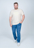 Homem usando camiseta plus size bege de malha botonê, com calça jeans e tênis brancos, posando em fundo neutro.