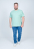 Camiseta plus size em malha relevo na cor verde claro, modelo masculino, com calça jeans e tênis branco.